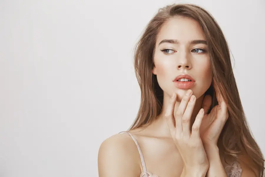 A close-up of a woman smiling confidently with smooth, naturally enhanced lips after a professional lip filler treatment. Bright, elegant medispa setting in the background.